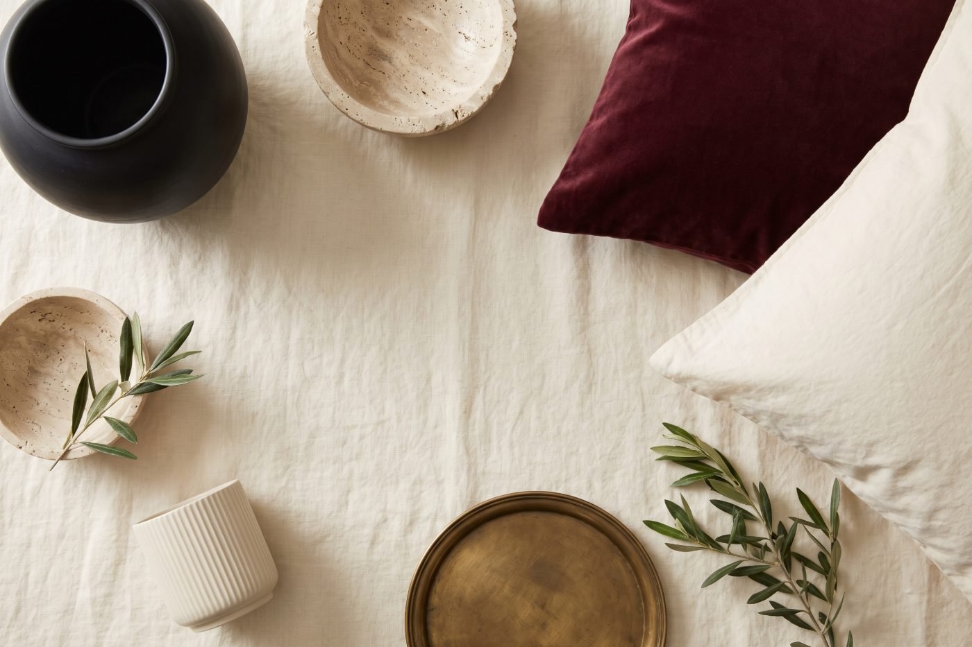 Designer-inspired home decor picks including a black ceramic vase, travertine bowl, velvet and washed cotton.