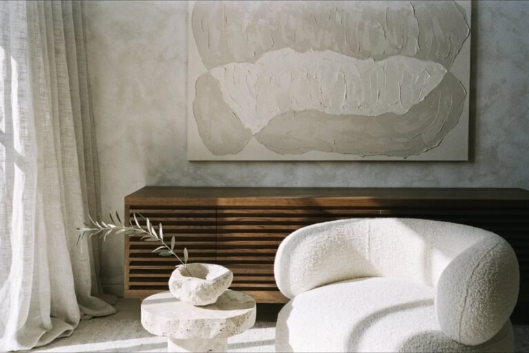 A restrained tonal living room in cream and greige with travertine, boucle and linen textures